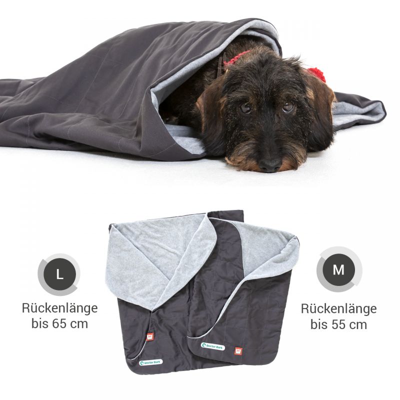 Hund schläft gemütlich in grauem Schlafsack, umgeben von einer hellgrauen Decke.