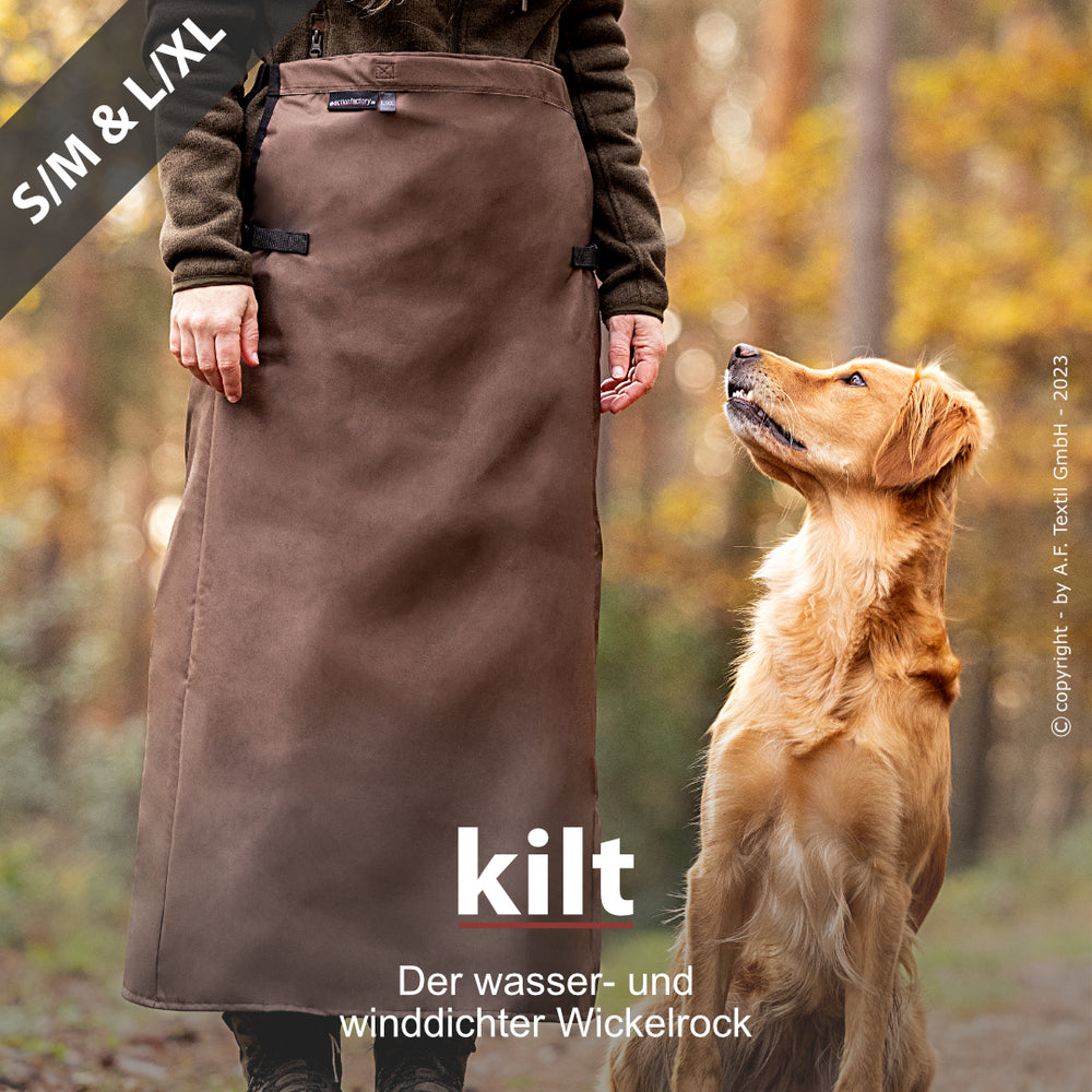Person im braunen Wickelrock mit Hund im Wald – wasser- und winddicht. Ideal für Outdoor-Aktivitäten.