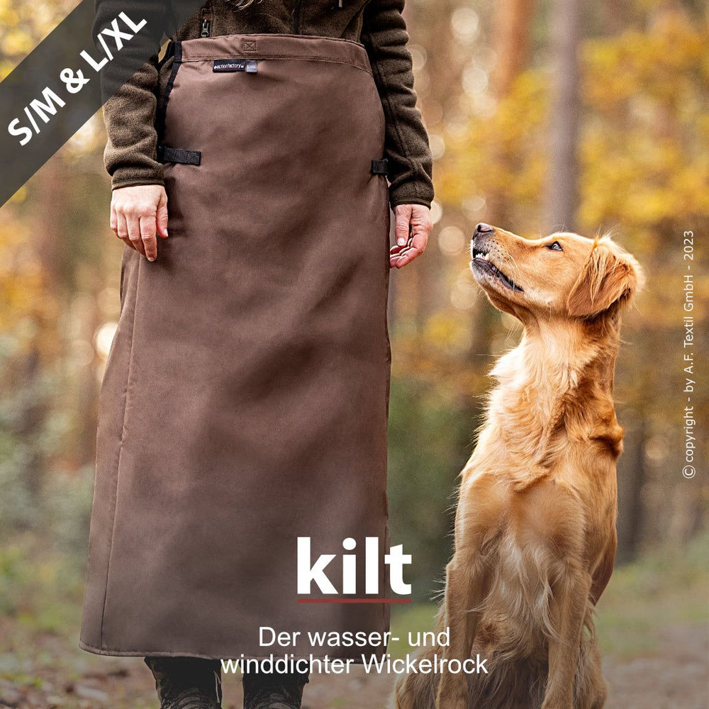 Person im braunen Wickelrock mit Hund im Wald – wasser- und winddicht. Ideal für Outdoor-Aktivitäten.