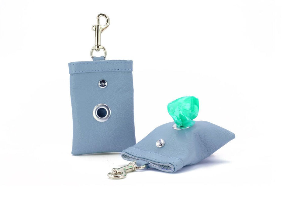 Blauer Leder-Hundekotbeutelspender mit Karabinerhaken und Druckknopföffnung, sichtbarer Kotbeutel herausragend.