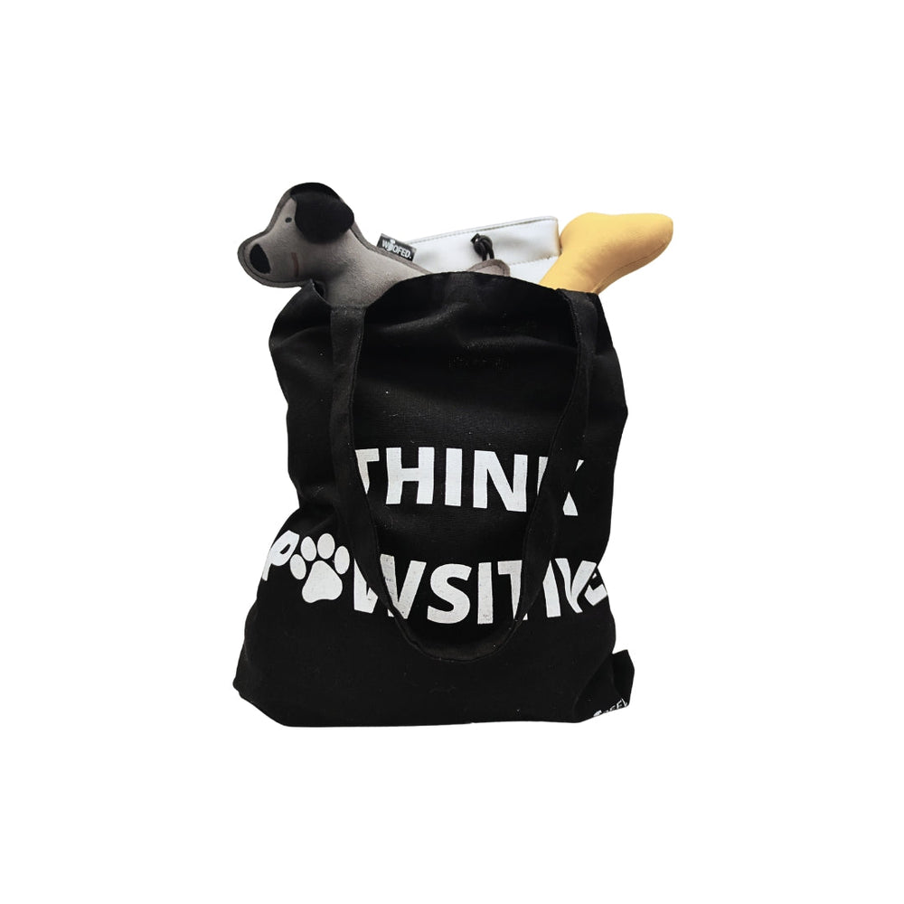 Baumwolltasche "Think Pawsitive" mit Hundespielzeug, ideal für Hundeliebhaber und umweltfreundlich im Alltag.