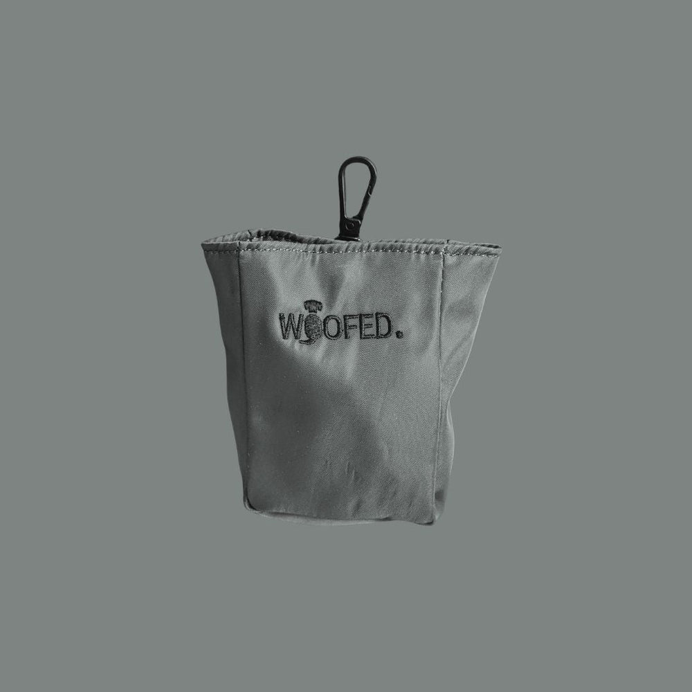 Graue Gassitasche mit "WOOFED." Schriftzug, faltbar und mit Clip zur Befestigung für Hunde-Leckerlis.
