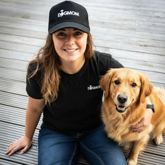 Frau mit Hund und "DOG MOM" Cap, lächelnd, zeigt Verbundenheit zu ihrem Vierbeiner im Alltag.