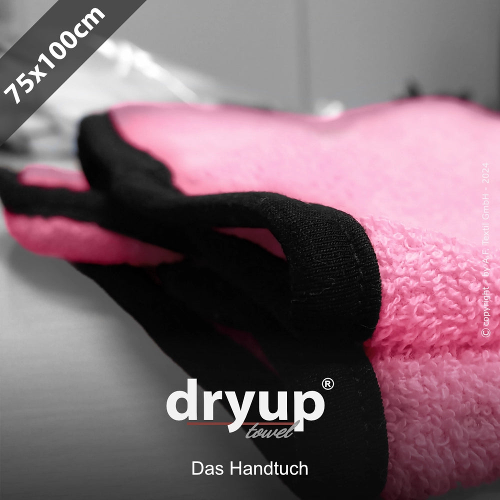 Pinkes Dryup® Handtuch mit schwarzen Kanten, zusammengelegt, 75x100 cm, auf einer Oberfläche platziert.
