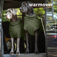 Zwei große Hunde im Fahrzeug mit grünen Umhängen von warmover©, ideal für gemütliche Fahrten.