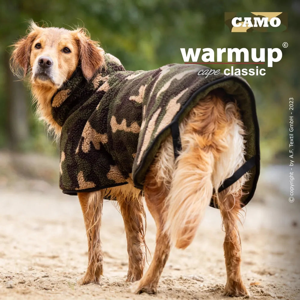 Hund im camouflage Kapuzen-Mantel aus Fleece auf sandigem Untergrund, bereit für ein warmes Abenteuer.
