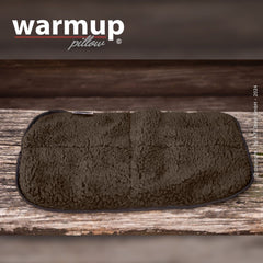 Rechteckiges warmes Kissen in plüschiger Textur auf Holzoberfläche mit sichtbar markiertem "warmup pillow"-Logo.