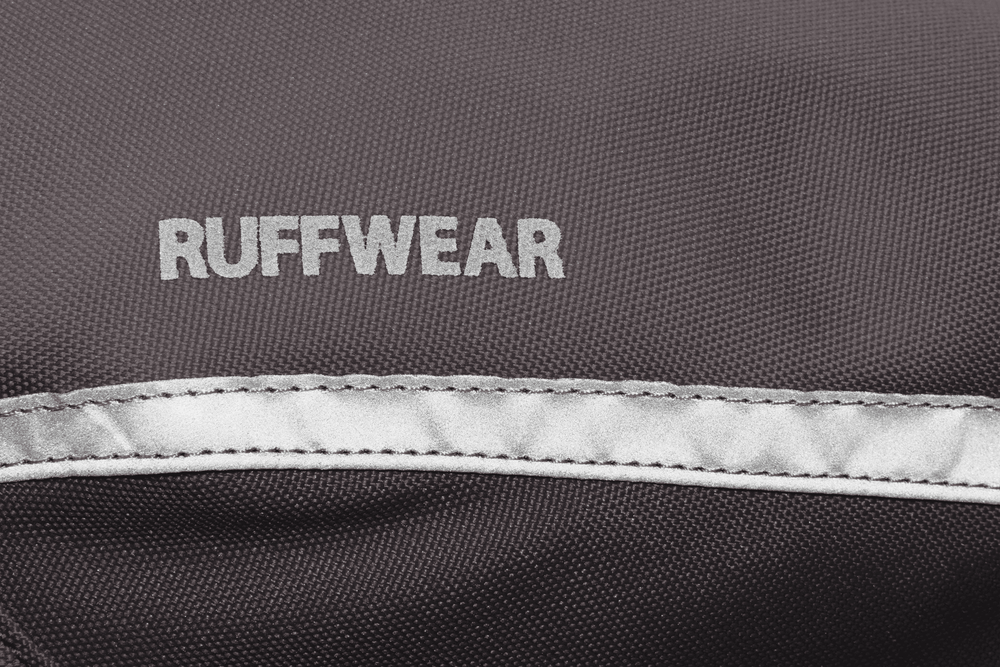 "Logo von RUFFWEAR auf grauem Stoff mit silberner Naht, unscharfer Hintergrund für klare Fokussierung."
