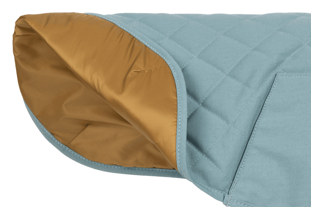 Gesteppter Hundemantel Stumptown™ in sanftem Blau mit warmem goldfarbenem Innenfutter. Ideal für kalte Tage.