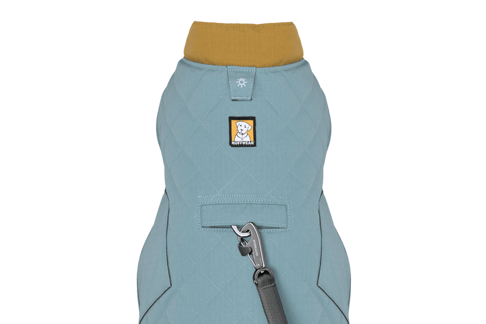 Helle blauer gesteppten Hundemantel mit gelbem Kragen und markantem Logo, ideal für kühle Tage.