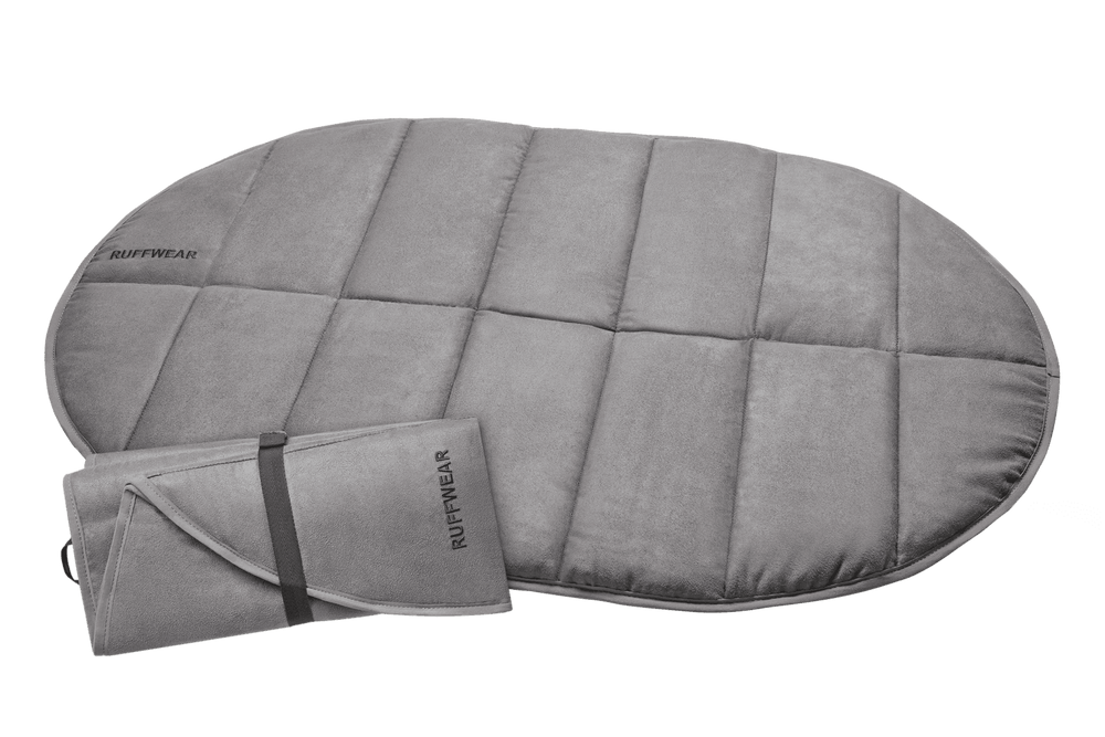 Graue ovalförmige Highlands™ Hunde Isomatte mit gestepptem Design und gefalteter Variante im Bild.