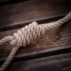 Zahnpflegender Zergel aus Hanfseil mit festem Knoten auf rustikaler Holzoberfläche.