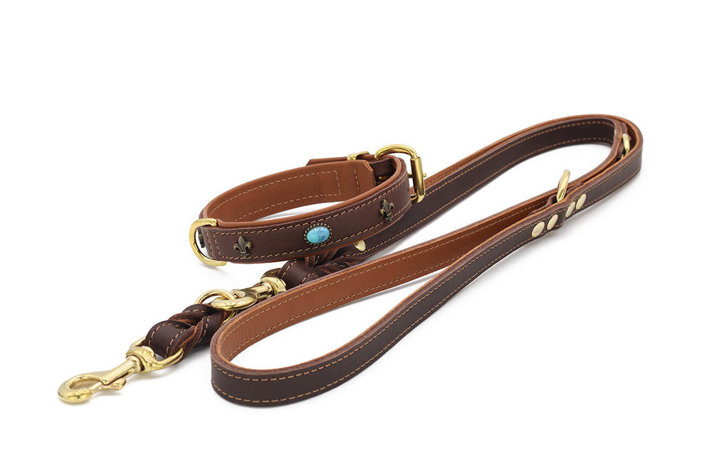 Braune geflochtene Hundeleine aus Leder mit goldfarbenen Beschlägen und blauem Schmuckstein, verziert mit floralen Mustern.
