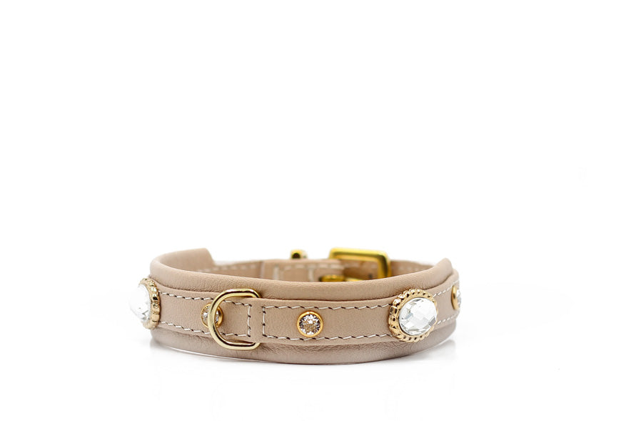 Elegantes hellbeiges Lederarmband mit goldfarbenen Elementen und glitzernden Steinen, klassische Schnalle.
