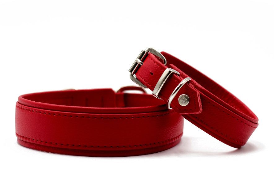 Rote Lederarmbänder: eines breit mit Naht, das andere schmal mit Metallschnalle, modern und stilvoll.