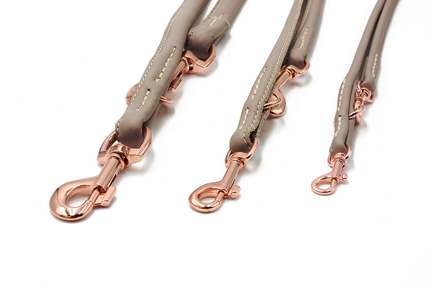 Drei graue Leder-Hundeleinen mit rose-goldenen Karabinern und hellen Nähten in verschiedenen Längen.