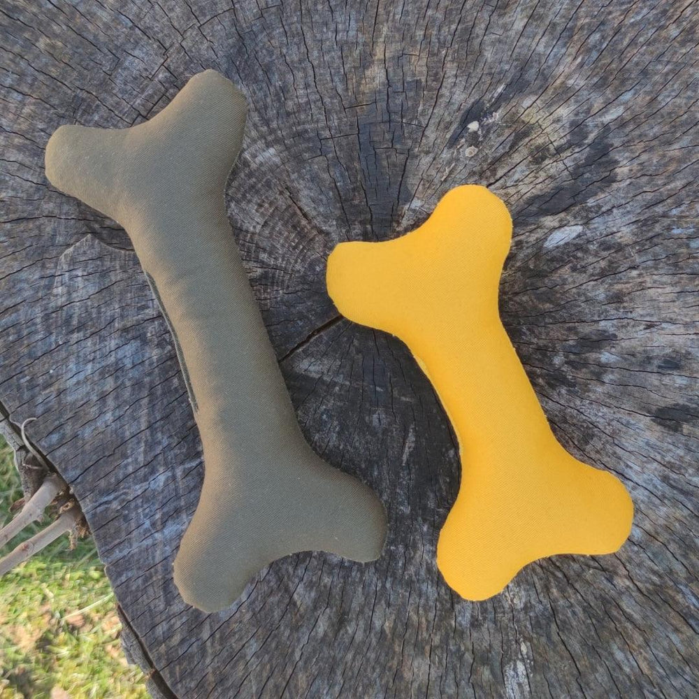 Hundespielzeug Stoffknochen Playbone in olivgrün und gelb, weich und ideal für Kuscheln und Apportieren auf Baumstamm.