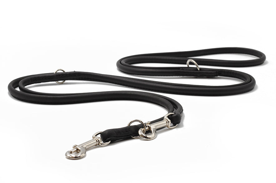 Schwarze, runde Lederleine 3m mit silbernem Karabiner und D-Ring, flach auf weißem Hintergrund.