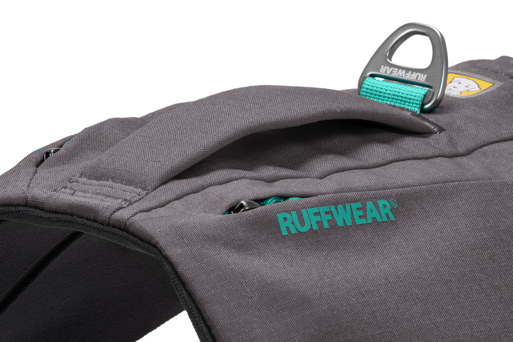 Graues Ruffwear Switchbak™ Hundegeschirr mit gepolsterter Oberfläche, Schlaufe und grünen Logo, ausgestattet mit seitlichen Taschen.