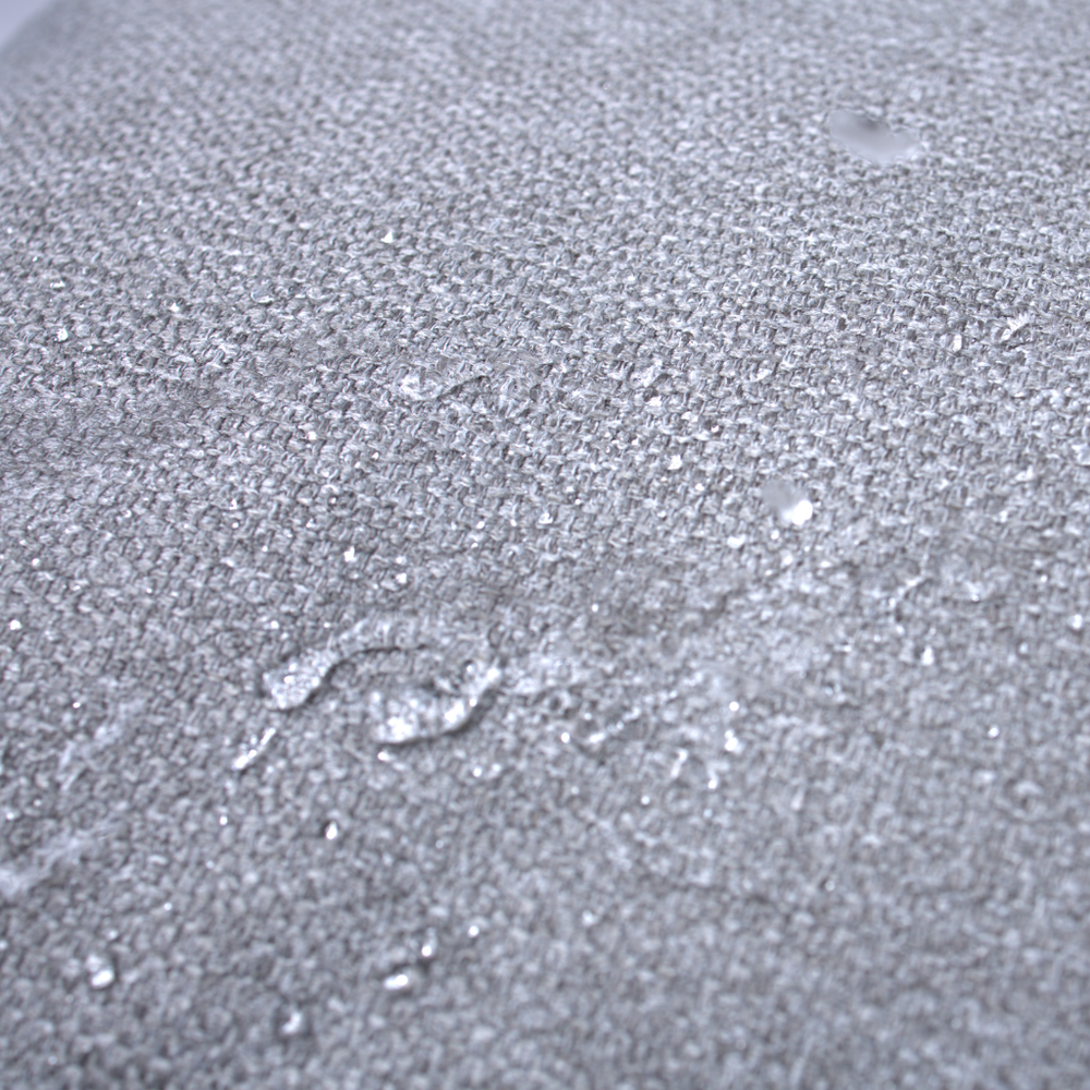 Graues Hundebett mit dichte gewebter Textiloberfläche, Wassertropfen zeigen wasserabweisende Eigenschaften des Materials.