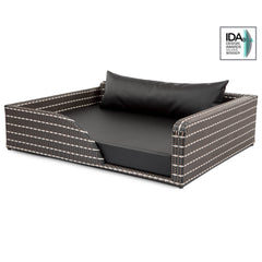 Elegantes Hundebett Cosmopolitan aus geflochtenem Material in dunklen Farben, rechteckig, mit schwarzem Kissen und Designpreis-Logo.