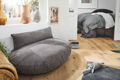 Helles LUNA LOUNGE SET - TUDOR in gemütlicher Wohnung mit grauem Sitzbereich und Korbstuhl.