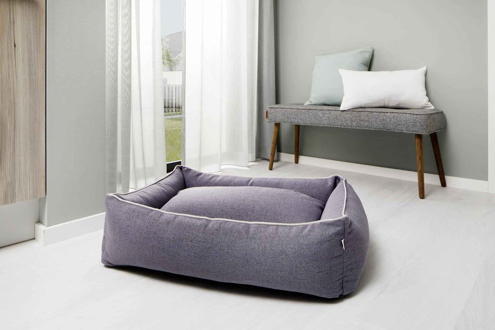 "CLASSIC Hundebett VITO in grauem Stoff, rechteckig, stilvoll neben gemütlicher Wohnumgebung mit Bank und Kissen."