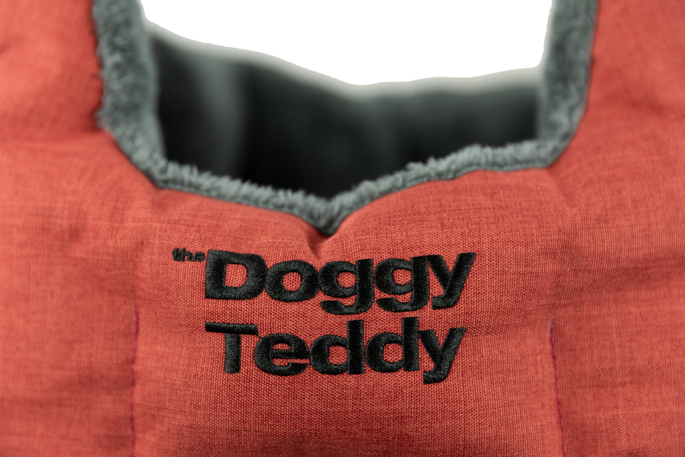 "Roter Stoff mit grauer, samtiger Innenseite und schwarzem Schriftzug 'the Doggy Teddy'."