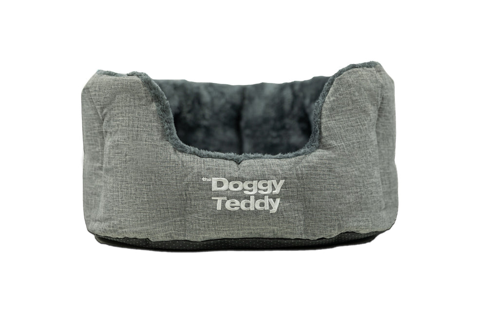 Hundefreundliches Bett in Grau mit weicher Wendeseite und "the Doggy Teddy"-Schriftzug für gemütlichen Schlaf.