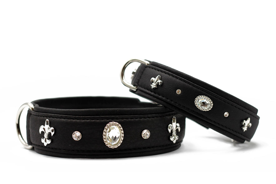 Schwarze Lederhalsbänder mit glänzenden Verzierungen und ovalem Stein, verziert mit silbernen Fleur-de-Lis-Motiven.