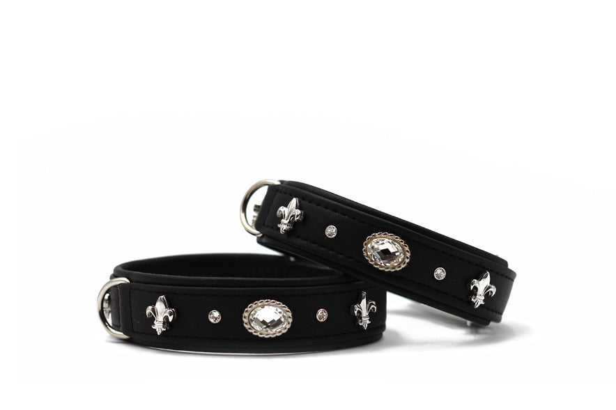 Schwarze Halsbänder aus strapazierfähigem Material mit silbernen Fleur-de-Lys-Motiven und glänzenden Schmucksteinen.