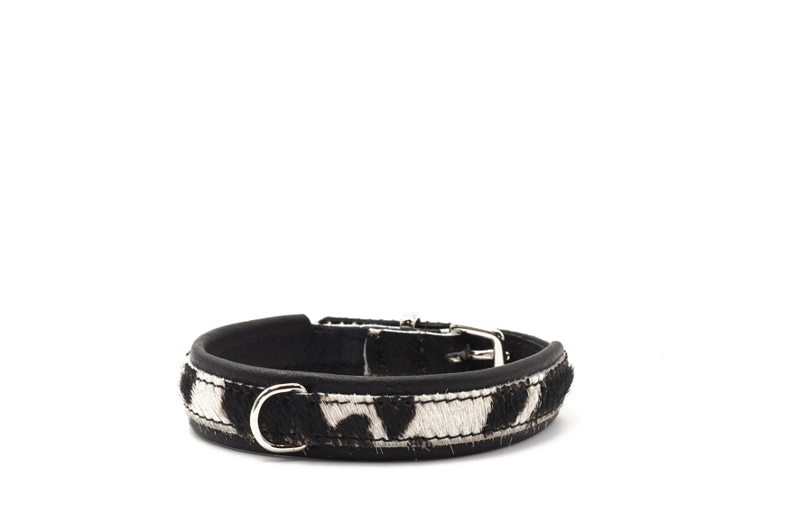 Halsband aus schwarzem Leder mit Kuhfellmuster in Schwarz und Weiß, verstellbar mit D-Ring für Leinenbefestigung.