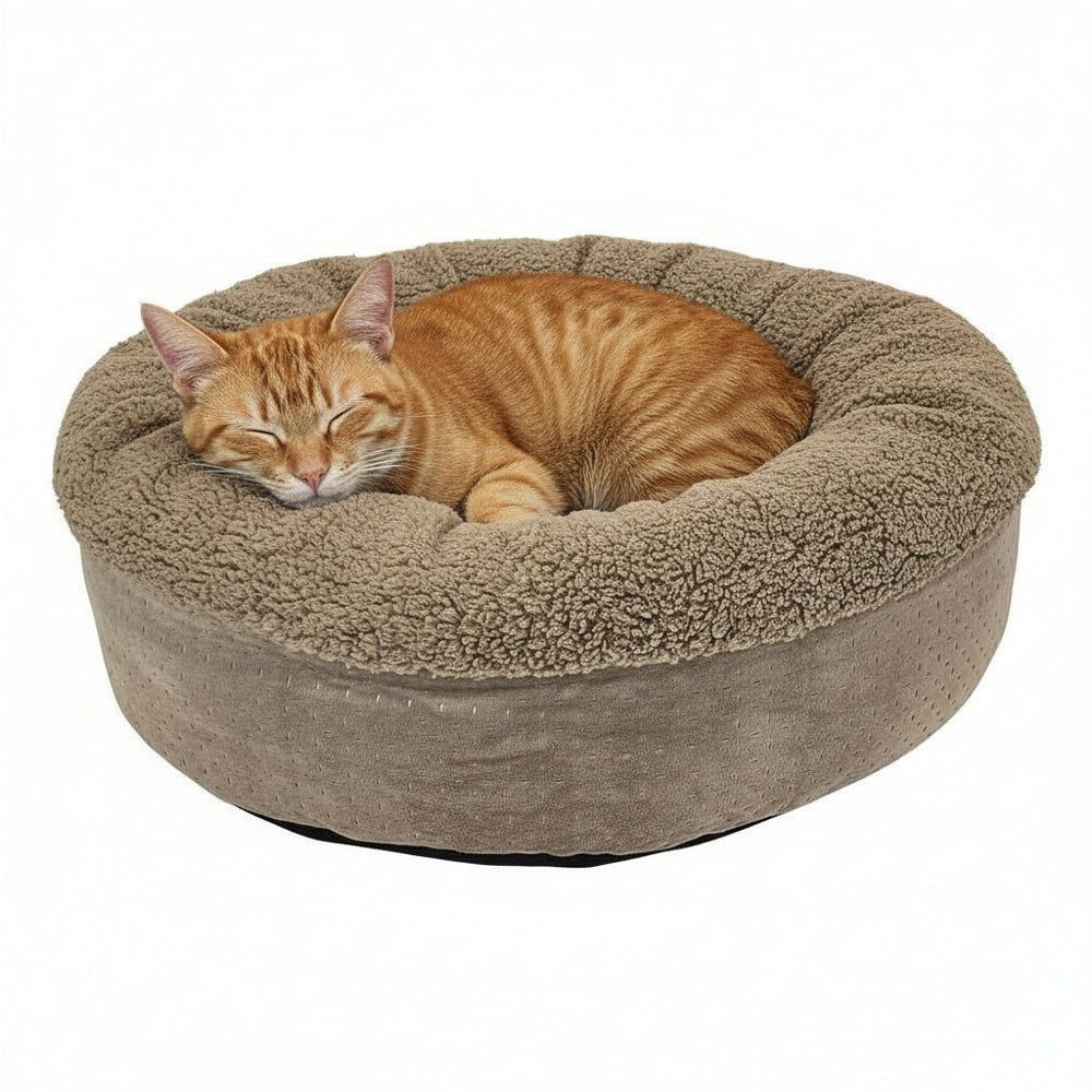 Rundes Katzenbett "TEDDY" in Beige mit flauschigem Rand, ideal für eine schlafende orangefarbene Katze.