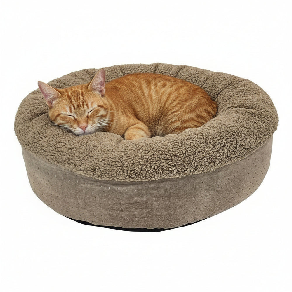 Rundes Katzenbett "TEDDY" in Beige mit flauschigem Rand, ideal für eine schlafende orangefarbene Katze.