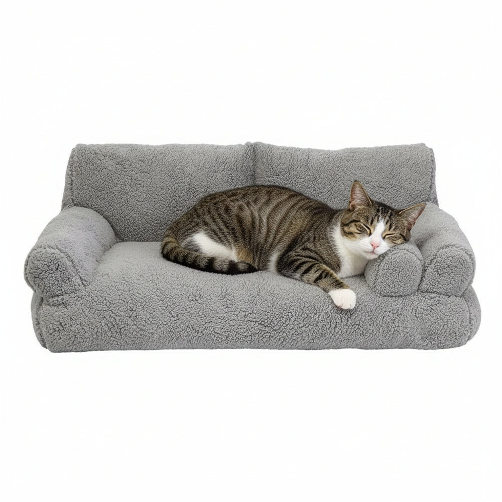 Gemütliches graues Katzenbett in Sofaposition, mit schläferischer gestreifter Katze darauf.