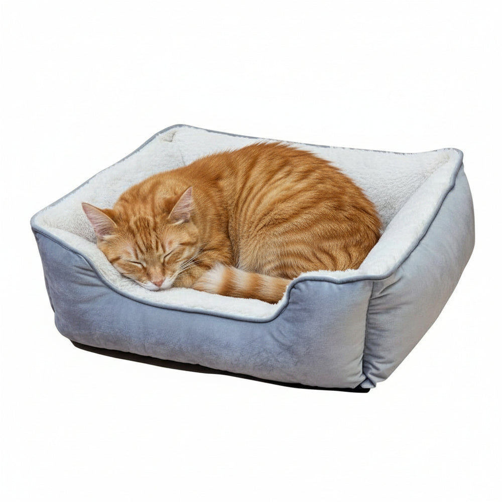 "Orange getigerte Katze schläft in einem bequemen, rechteckigen Katzenbett mit grauer Außenfläche und plüschigem Innenfutter."