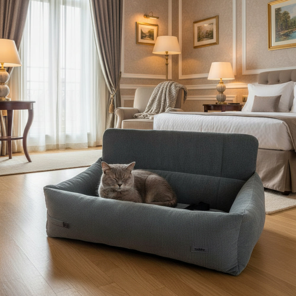 Stilvolles Zimmer mit Ehebetten, eleganten Möbeln und einer schlafenden grauen Katze im grauen Katzenbett.