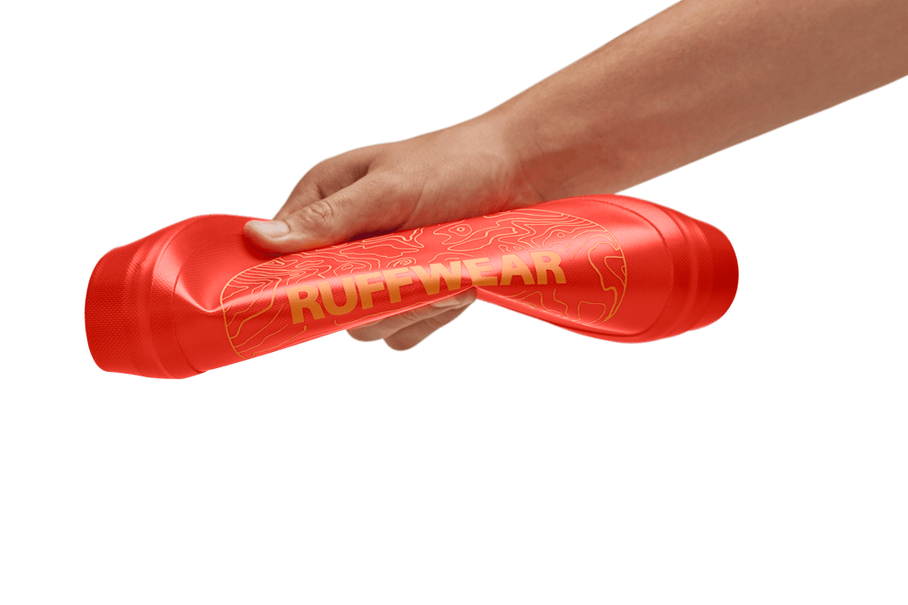 Roter Camp Flyer™ Frisbeescheibe von Ruffwear, handgehalten mit einer strukturierten Oberfläche für Hunde.