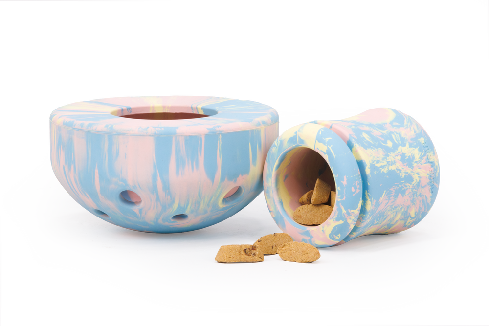 Pastellfarbene Porcini™ Futterbehälter für Haustiere, einer aufrecht, der andere mit Keksen auf der Seite.