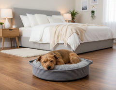 Entspannter Hund schläft auf rundem grauen Hundebett "Nola" in gemütlichem Schlafzimmer.