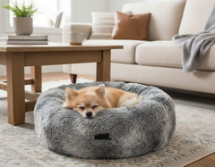 "Rundes Komfortbett Donut 'Coda' für Hunde mit schlafendem Pomeranian auf Teppich."