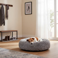 Gemütliches rundes Komfortkissen Ares für Hunde auf hellem Boden mit Hund in der Mitte des Raumes.