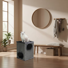 Grauer Katzenwürfel ADRA in modernem Raum, Katze sitzt darauf, minimalistische Einrichtung mit großen Fenstern.