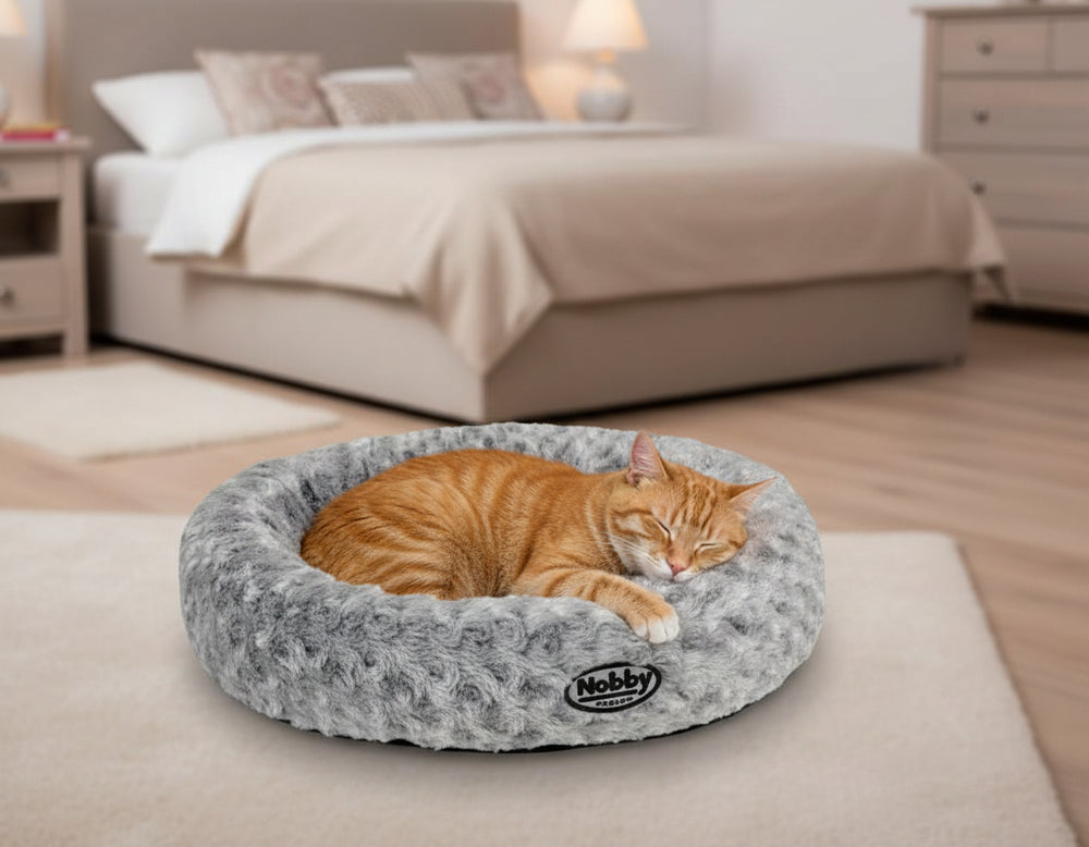 Gemütliches Katzenbett in Korbform mit schlafender orangefarbener Katze im Schlafzimmer.