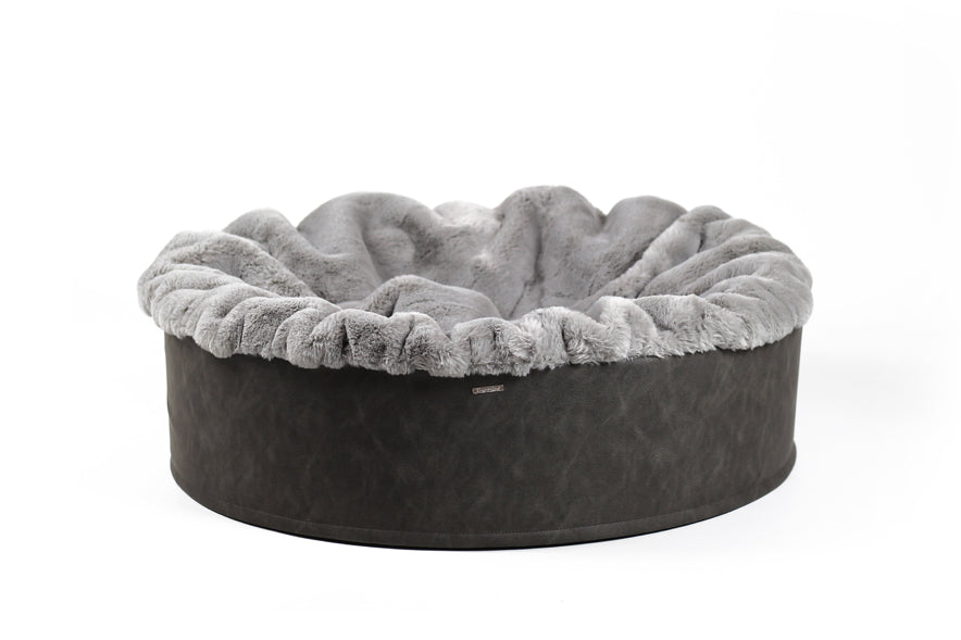 Rundes Hundebett Buddelnest® mit grauem, flauschigem Innenfutter und dunklem, wellenförmigem Außenrand.