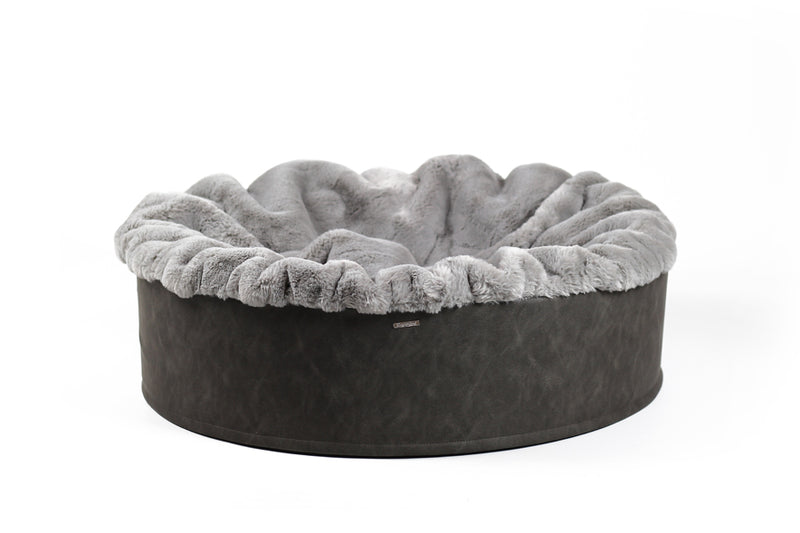 Rundes Hundebett Buddelnest® mit grauem Plüsch und dunklem Außenrand, perfekt zum Kuscheln und Entspannen für Hunde.