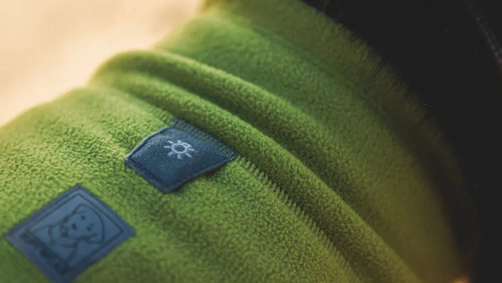 Grüne Climate Changer™ Fleeceweste aus weichem Material mit Sonnenlogo und Markenetikett, ideal für kalte Tage.
