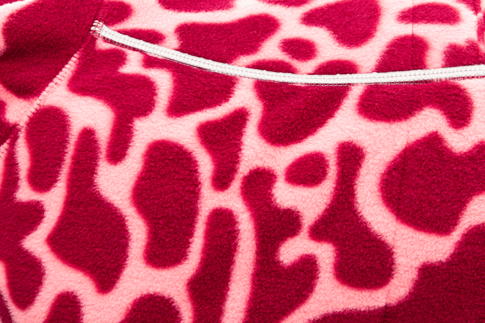 "Climate Changer™ Fleeceweste mit Giraffenflecken-Muster in Rot- und Pinktönen, ideal für modische Outfits."
