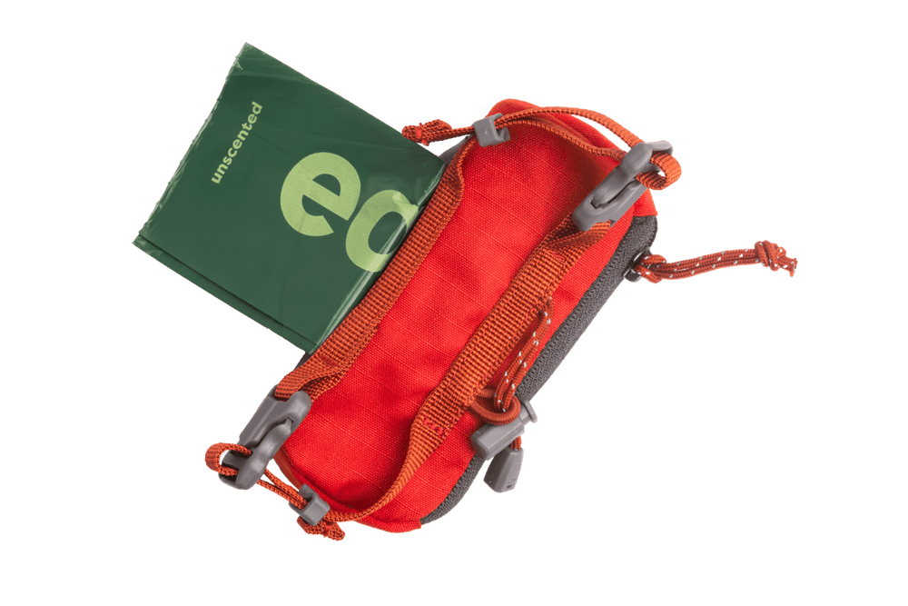 Rote Neopren-Stash Bag Mini™ mit grauen Reißverschlüssen und grünem, gefaltetem Inhalt – ideal für Abholungen.