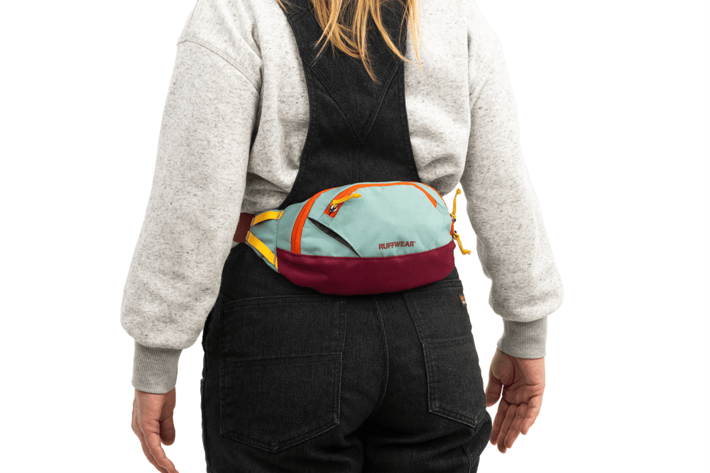 Bunte Home Trail™ Hüfttasche in Hellblau und Maroon, getragen von einer Person in grauem Sweatshirt.